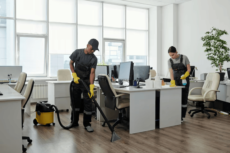 young-black-man-workwear-cleaning-floor-while-girl-wiping-desks-with-computers_274679-35141
